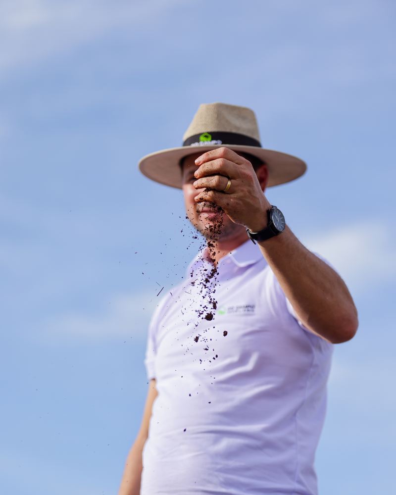 Luciano jogando terra para o alto contra o céu azul