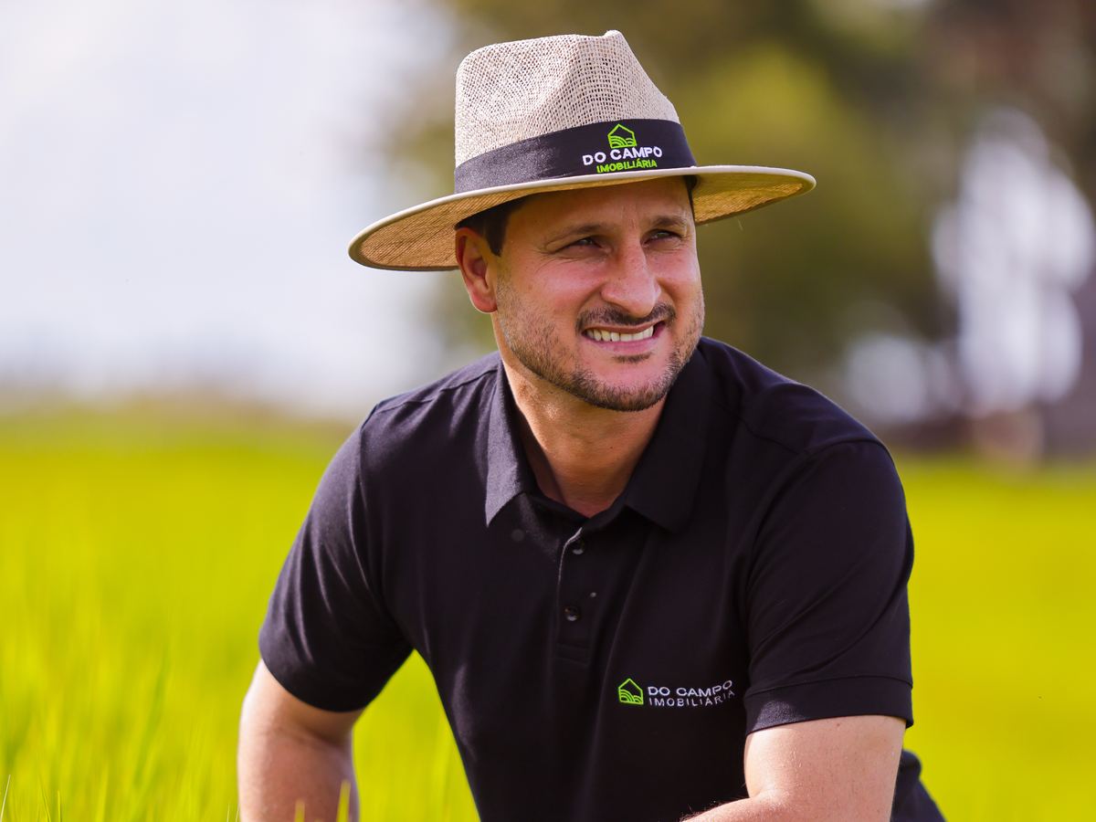 Luciano ajoelhado na lavoura, sorrindo