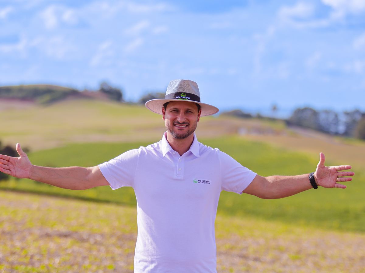 Luciano de braços abertos em uma área de plantio